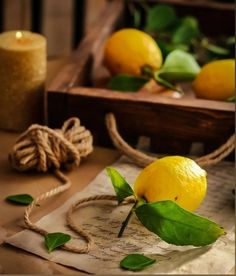 two lemons are sitting on a table next to some twine rope and candles