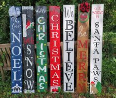 wooden christmas signs are lined up on the ground in front of some bushes and trees