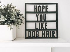 a black and white sign that says hope you like dog hair next to a potted plant