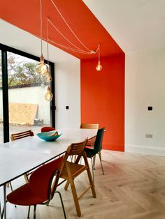 an orange and white dining room with wooden flooring, large windows, and modern lighting fixtures