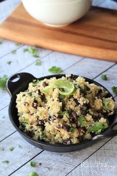 a black bowl filled with food on top of a wooden table