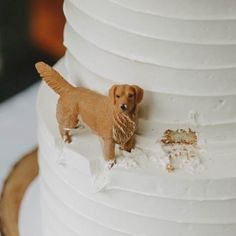 a dog figurine is standing on top of a white tiered wedding cake