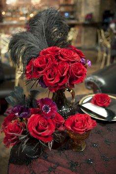 red roses are in a vase on a table with other flowers and decorations around it