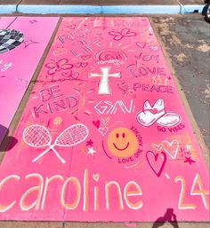 a pink sidewalk with some writing on it and two tennis rackets in the background