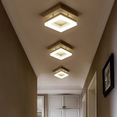 three lights are hanging from the ceiling in a hallway with beige walls and white doors