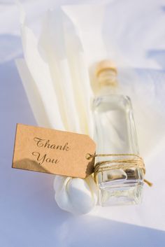 a bottle of thank you next to some cotton swabs on a white table cloth