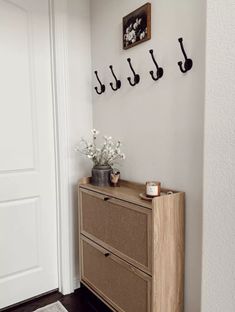 a wooden dresser sitting next to a white door with hooks on the wall above it