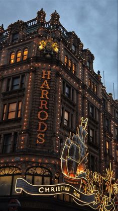 a large building with lights on it's sides and a sign that says harros