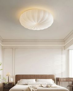 a large white bed sitting in a bedroom next to a table and lamp on the wall