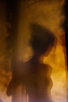 a blurry image of a woman standing in front of a window with her back turned to the camera