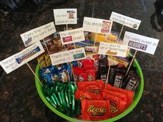 a green bowl filled with lots of candy on top of a black counter next to a sign