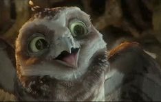 an owl with big green eyes is looking at the camera and has it's mouth open