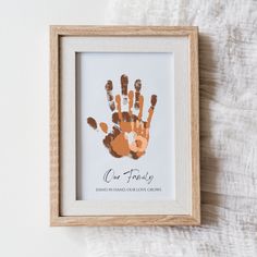 a hand print in a wooden frame on a white background with the words one family