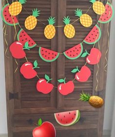 an apple, watermelon and pineapple garland hanging from a wooden door