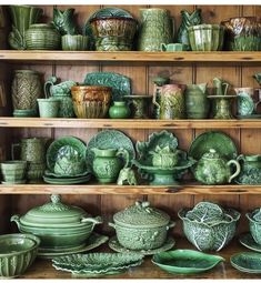 a shelf filled with lots of green dishes and vases on top of wooden shelves