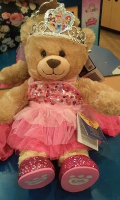 a brown teddy bear wearing a pink dress and tiara