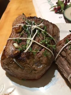 two steaks are sitting on a plate with garnishes and sprigs