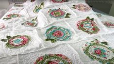 a quilted table cloth with many different designs on it, including flowers and leaves