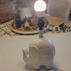 an elephant lamp sitting on top of a table next to a plate with other items