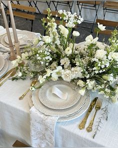 the table is set with white flowers and silverware