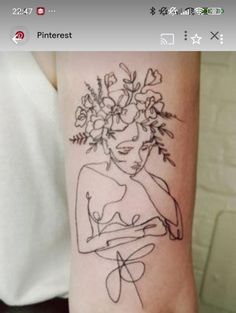 a woman's arm with a tattoo on it that has flowers in her hair