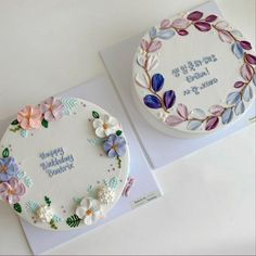 two decorated cakes sitting on top of a table next to each other in front of a card