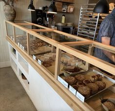 a man standing in front of a display case filled with pastries