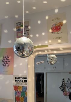 a mirror ball hanging from the ceiling in a room with polka dot wallpaper and posters on the walls