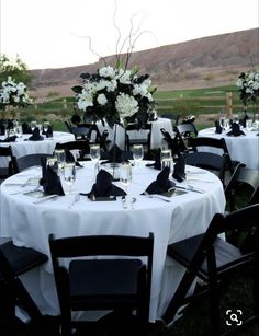 the table is set with black and white linens for an elegant wedding reception in the mountains