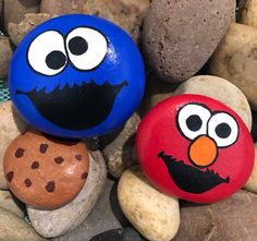 two painted rocks with faces on them sitting next to some rocks and stones that have been placed together