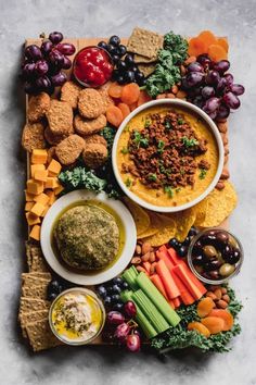 a platter filled with crackers, dips and veggies is shown