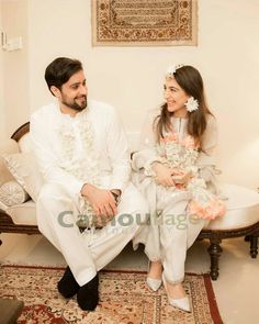 a man sitting next to a woman on top of a white couch in a living room