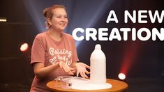 a woman standing in front of a table with a bottle on it that says a new creation