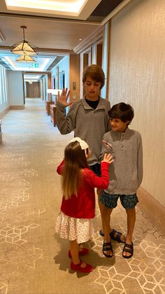 two children are standing in the hallway with their hands up and one child is holding his hand out