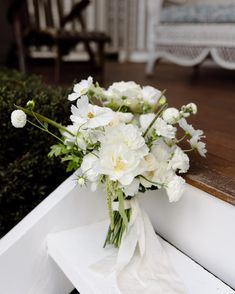 a bouquet of white flowers sitting on top of a bench