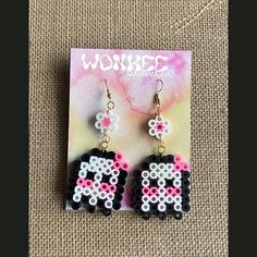 a pair of black and white earrings with pink beads on top of a piece of paper