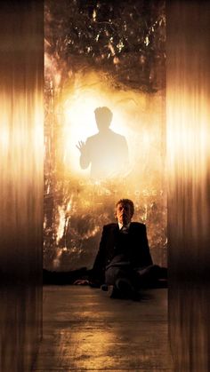 a man sitting on the ground in front of a wall with light coming through it