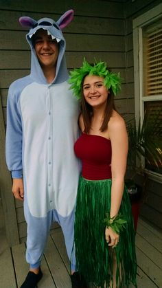 two people dressed up in costumes standing on a porch with their arms around each other