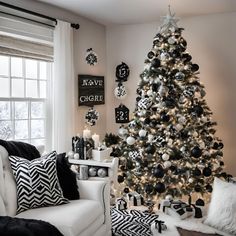 a living room with a christmas tree and black and white decorations on the walls,