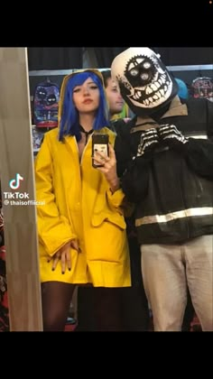 two people in costumes standing next to each other and looking at a cell phone screen