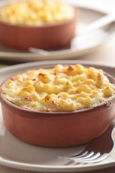 a dish with macaroni and cheese in it on a plate next to a fork