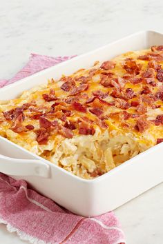 a casserole dish with bacon and cheese in it sitting on a pink towel