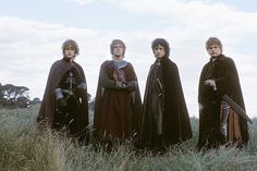 four men dressed in medieval costumes standing in tall grass