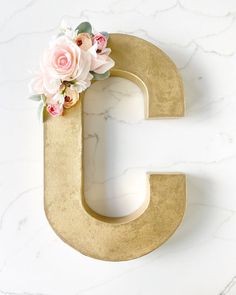 the letter g is decorated with flowers on top of it's gold metal frame