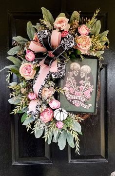 a wreath with pink flowers and skulls is hanging on the front door, next to a framed photo