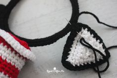 a crocheted red and white bag with a black hook on it's end