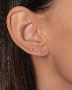 a close up of a woman's ear with three small diamond studs