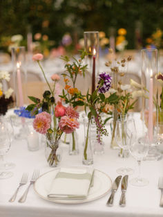 the table is set with flowers, candles and napkins for an elegant wedding reception