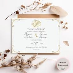 an elegant wedding card with gold foil on it and some dried flowers next to it