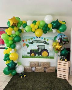 a tractor themed birthday party with green, yellow and white balloons on the wall above it